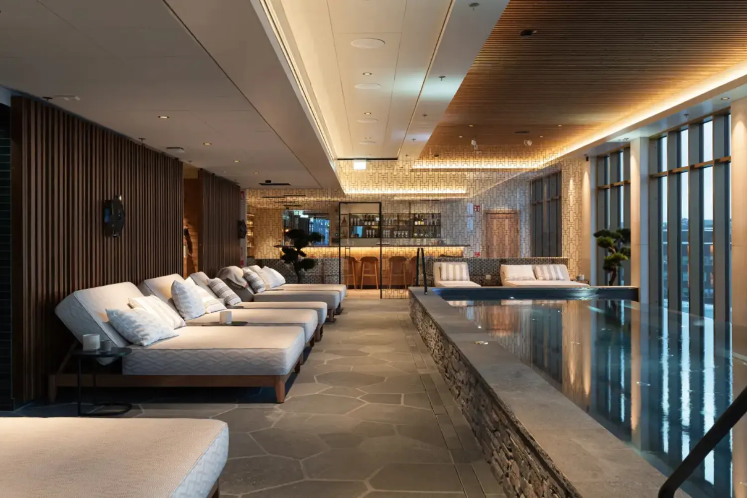 The cozy indoor pool at Vana Spa, Elite Hotel Frost in Kiruna, surrounded by plush loungers and a stylish bar in the background."