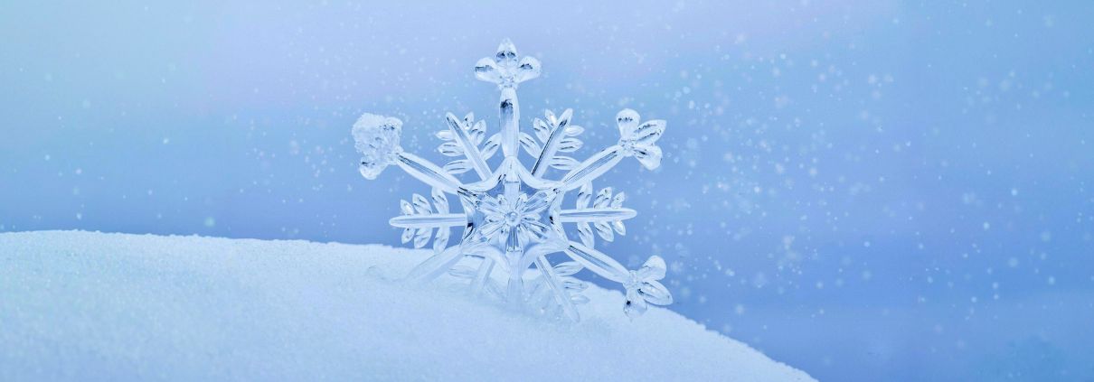 A delicate ice snowflake rests on white snow against a stunning blue background, capturing the magic of winter at the Kiruna Snow Festival.